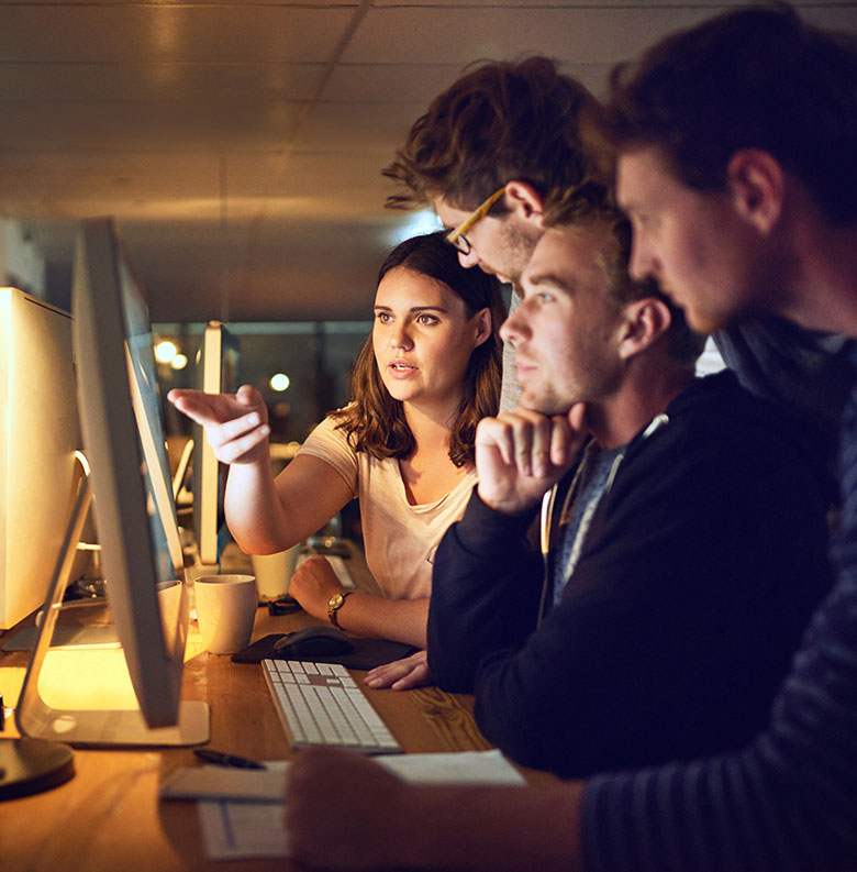 Diverse technology team collaborating at computer workstations